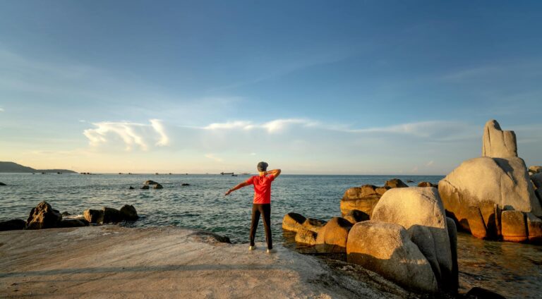 A person practices yoga at a rocky beach in Tây Ninh, Vietnam, enjoying a tranquil morning by the sea.
