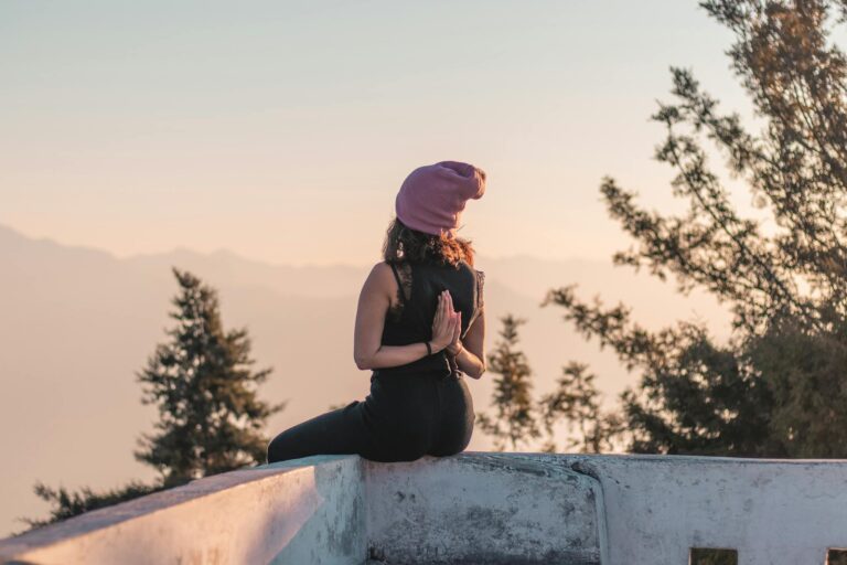 A woman meditating in reverse prayer pose on a rooftop in Rishikesh, India.